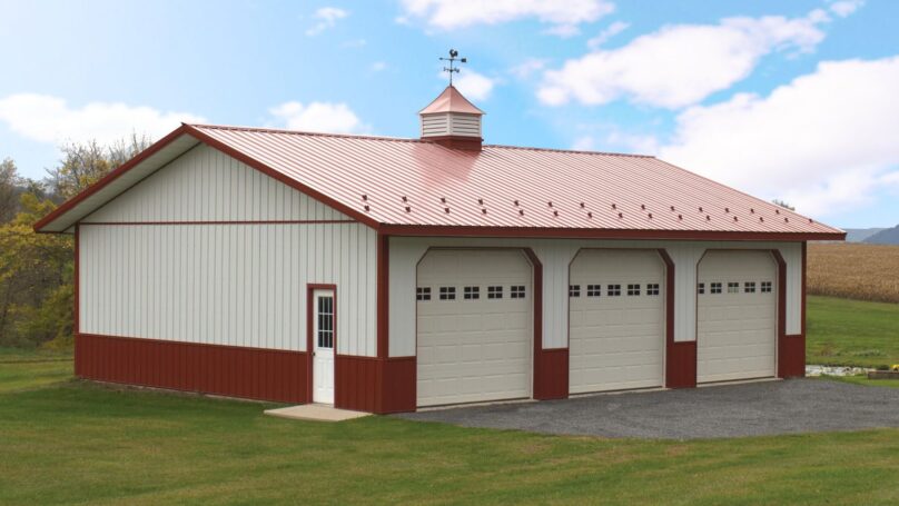 32x40 Residential post-frame white pole barn with red roof and trim, 3 garage doors with windows, cupola with weathervane, wainscoting, and snow guards