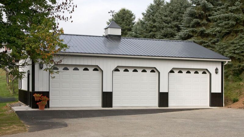 109-30′ x 40′ White Pole Building with Black Roof and Cupola 30x40 white pole barn with black roof and trim, three garage doors with windows, shutters, cupola, and wainscoting
