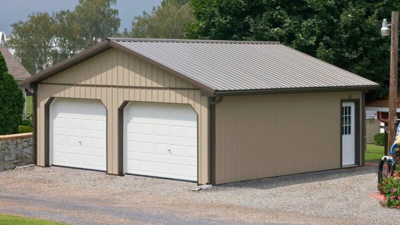 24x24 clay pole barn with bronze roof and trim, two insulated garage doors, entry door, and rain gutters