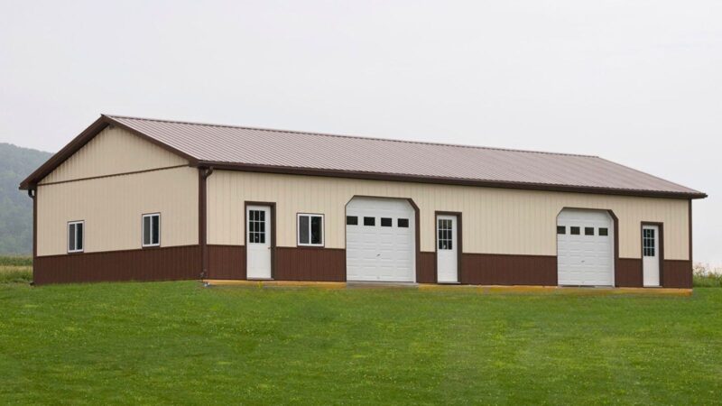 30x64 beige pole barn with brown roof and trim, garage doors with windows, three entry doors, sliding windows, and wainscoting
