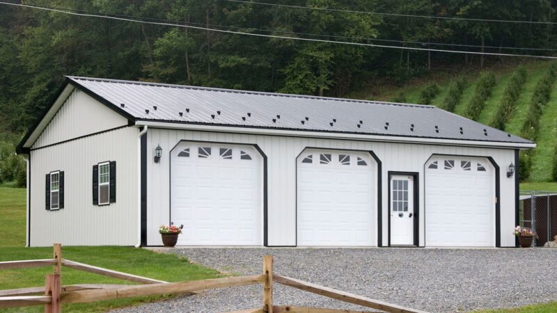 30x40 bone white pole barn with black roof and trim, three garage doors with windows, shutters, snow guards, and gutters