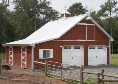 Agricultural pole barn with 2 bays, red siding and white roof with cupola