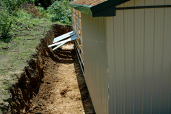 tan metal siding with wide ditch by building