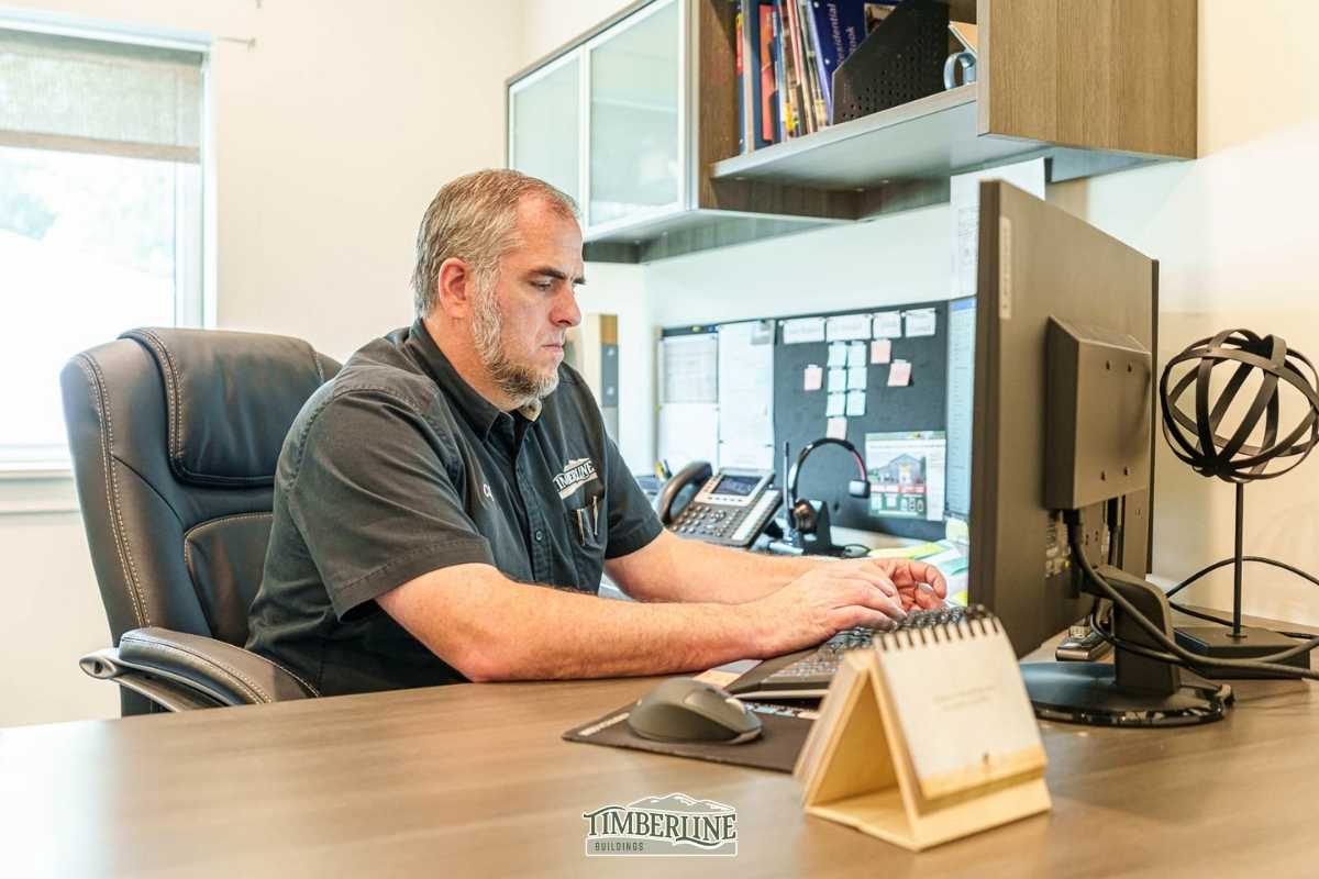 Timberline representative working at a desk, ready to provide a free pole barn investment quote