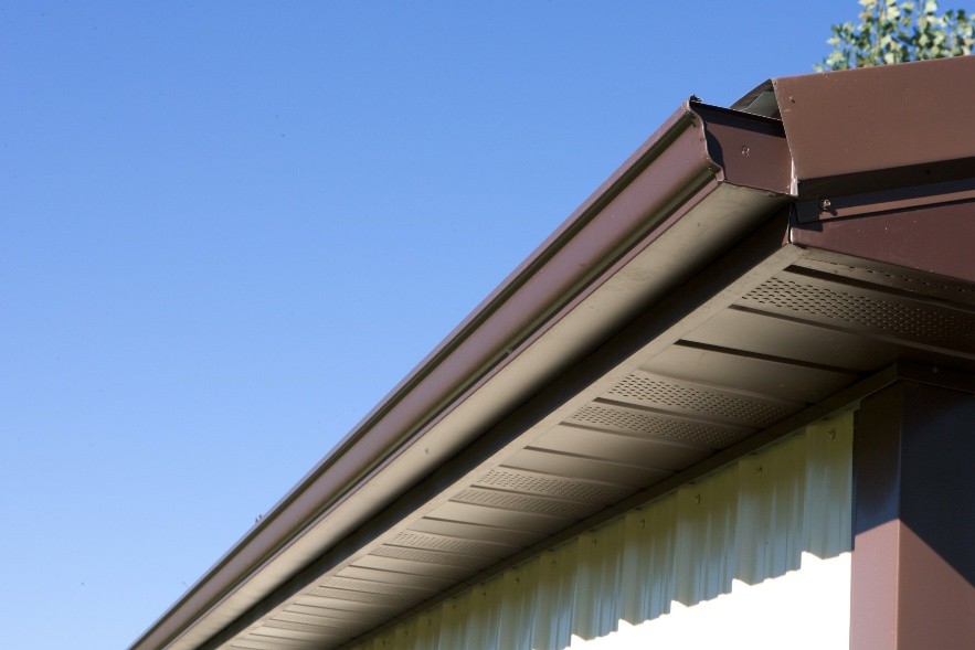 Brown Metal Rain Gutter Close-Up Brown rain gutter and fascia detail on a metal pole barn roof