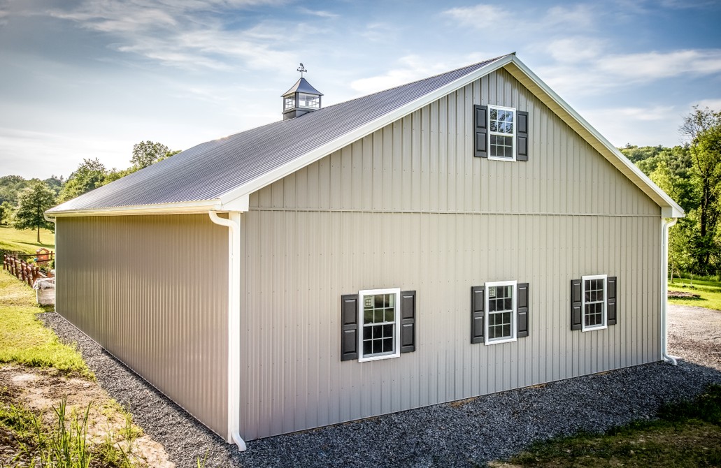 White Equine or Agricultural Barn with Gutter Light gray equine or agricultural pole barn with white rain gutters and cupola