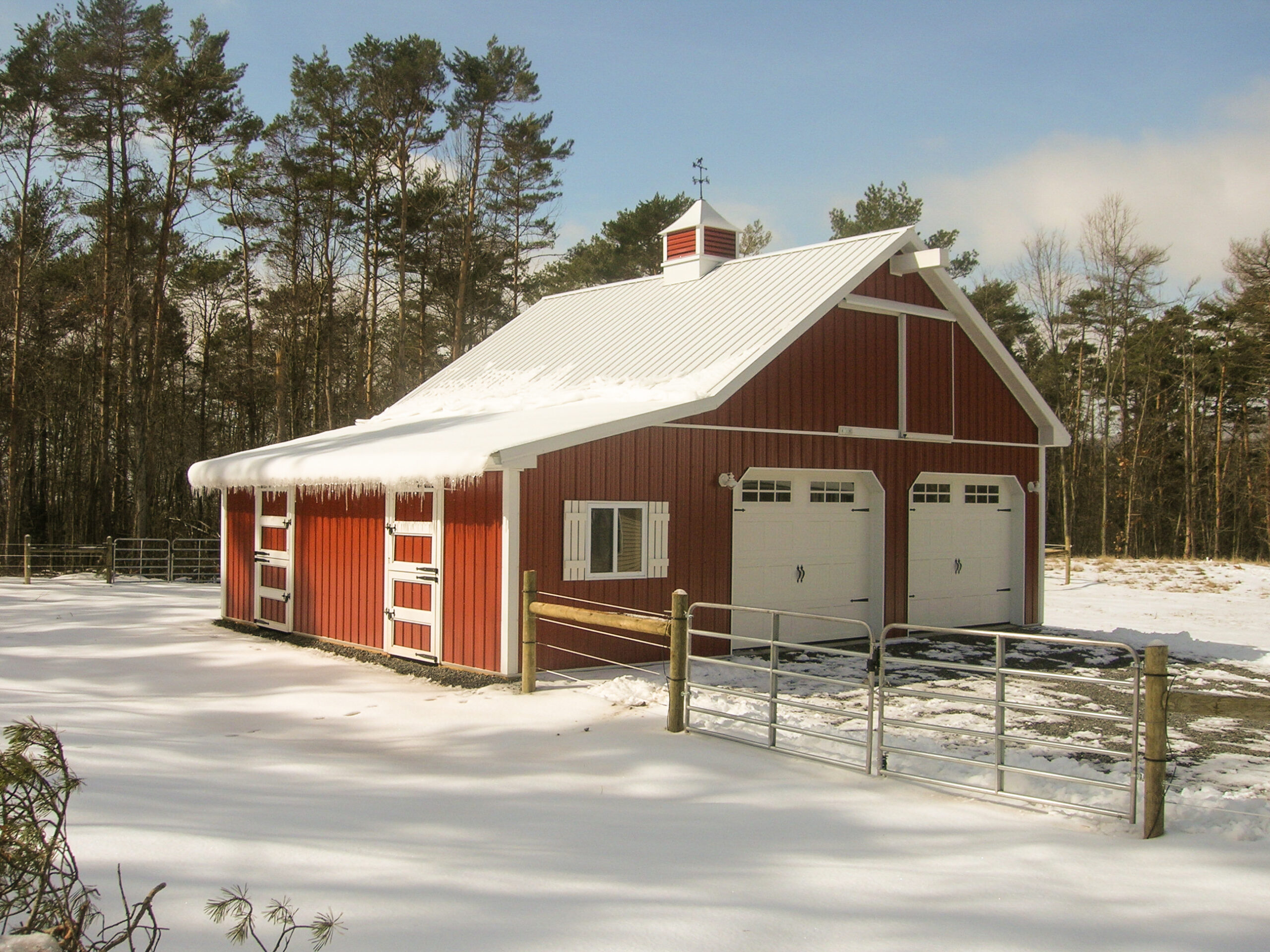 Red pole building with white trim and green roof in winter snow, promoting Timberline Buildings $800 off interior insulation package
