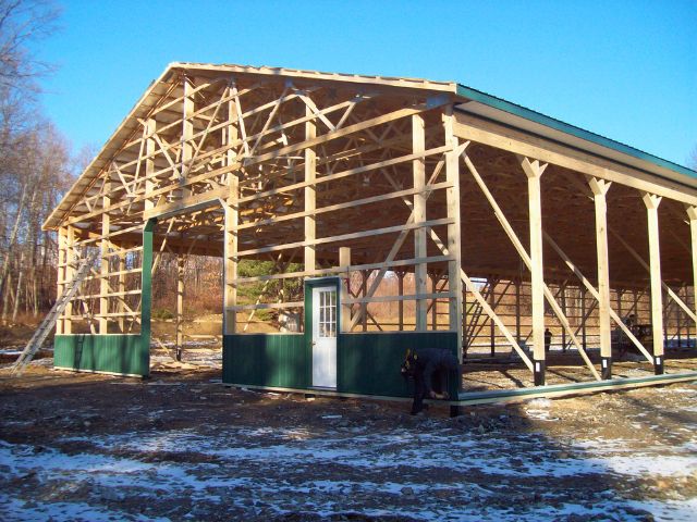 Timberline Buildings crew assembling a post-frame structure in winter with framing materials ready for installation.
