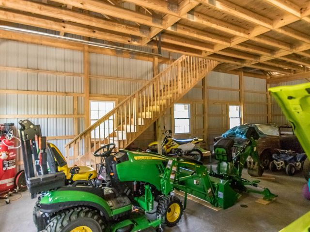 Spacious pole barn interior with workbenches and equipment, ideal for business or agricultural use