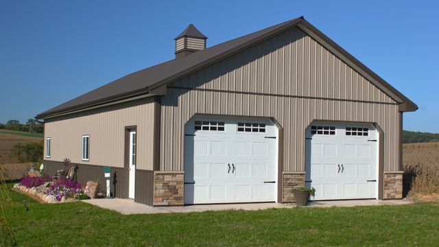 Custom residential pole building with two garage doors and cupola roof design by Timberline Buildings