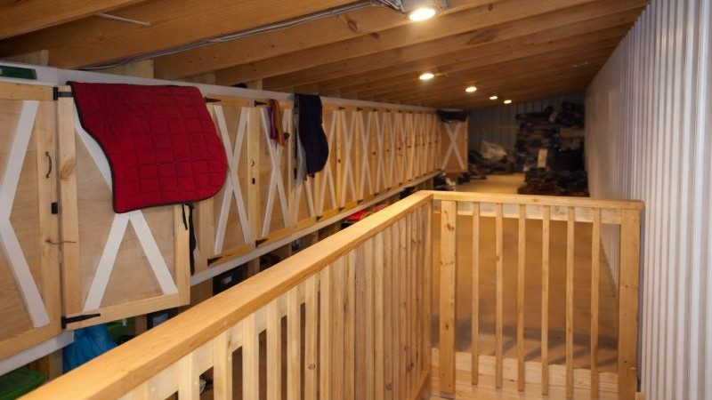 Loft overlooking stalls with wood railing and tack storage