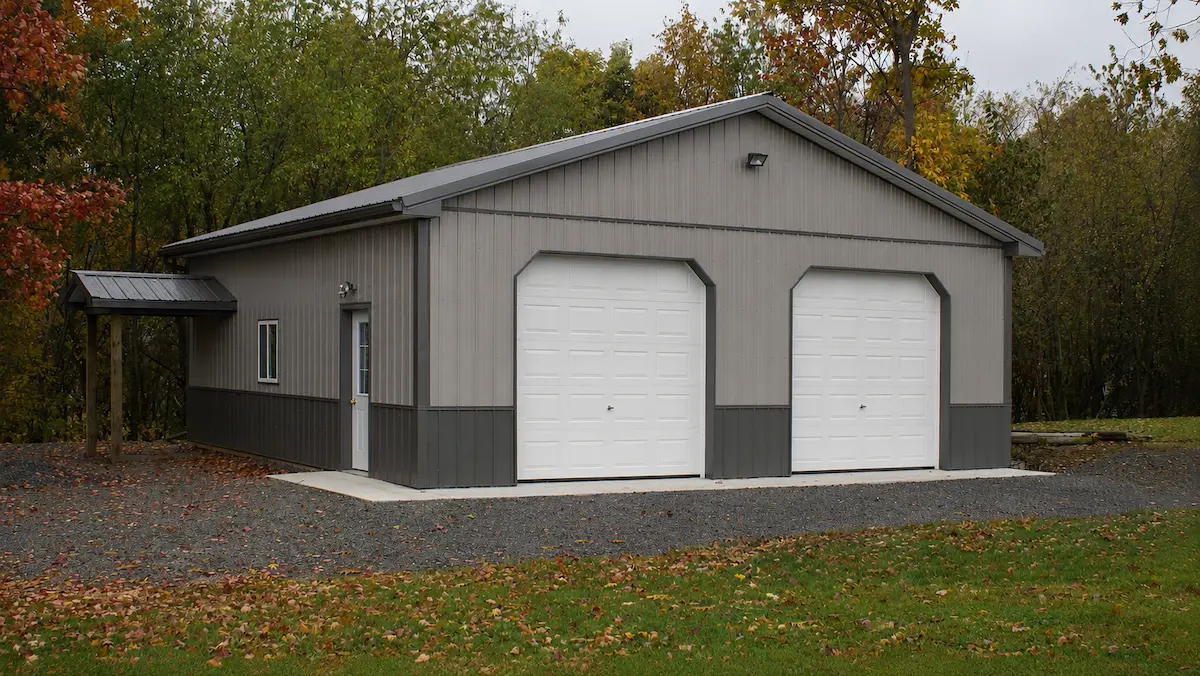 Residential Pole Barn Garage 30x32 pewter gray pole barn with charcoal roof and trim, two garage doors, entry door, sliding windows, wainscoting, and reverse A roof