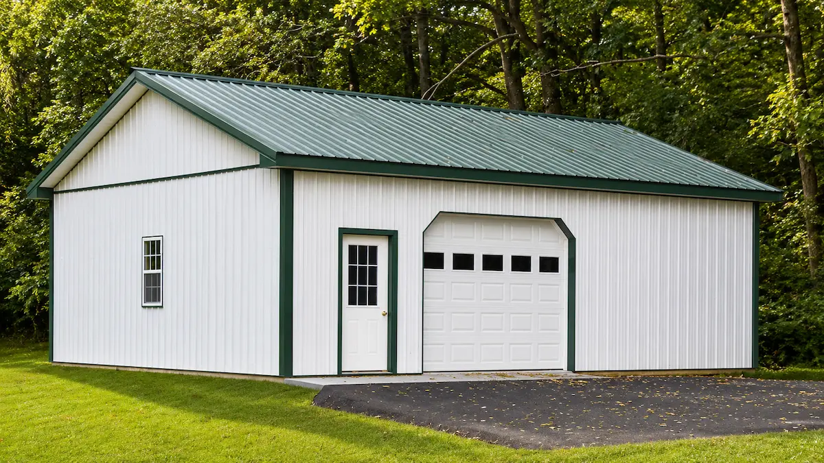 30x32 white pole barn with evergreen roof and trim, garage door with windows, entry door, and single hung window