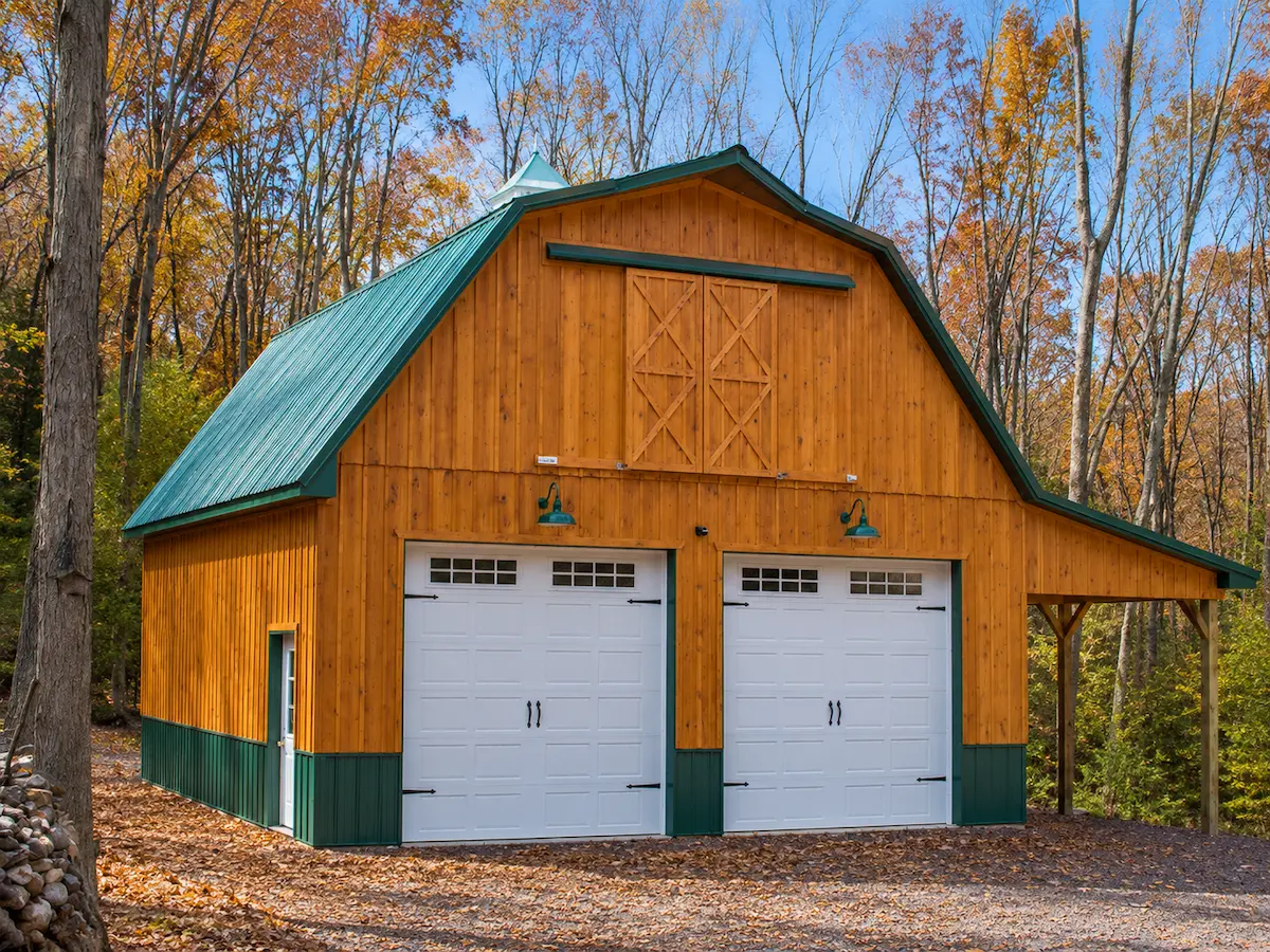 28x30 Pennsylvania pole garage for vehicle storage with board & baton siding, evergreen roof and trim, open sided lean-to, carriage style garage doors, wooden sliding door, and cupola with weathervane