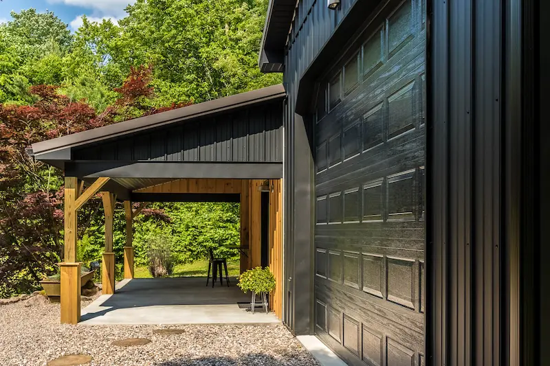 Custom pole barn with black metal siding, timber porch, and exterior finish upgrades in Pennsylvania