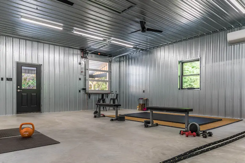 Finished post-frame building interior with insulation, lighting, and workout space