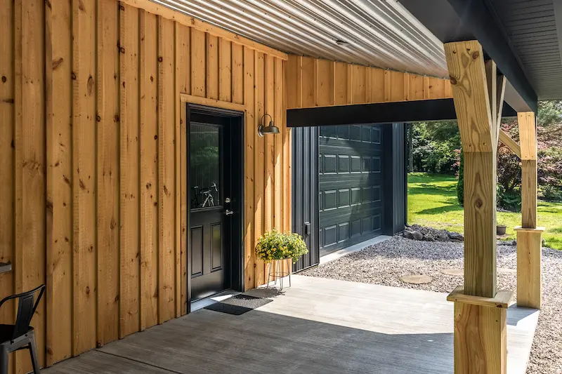 Residential pole barn featuring an insulated overhead garage door and upgraded entry door