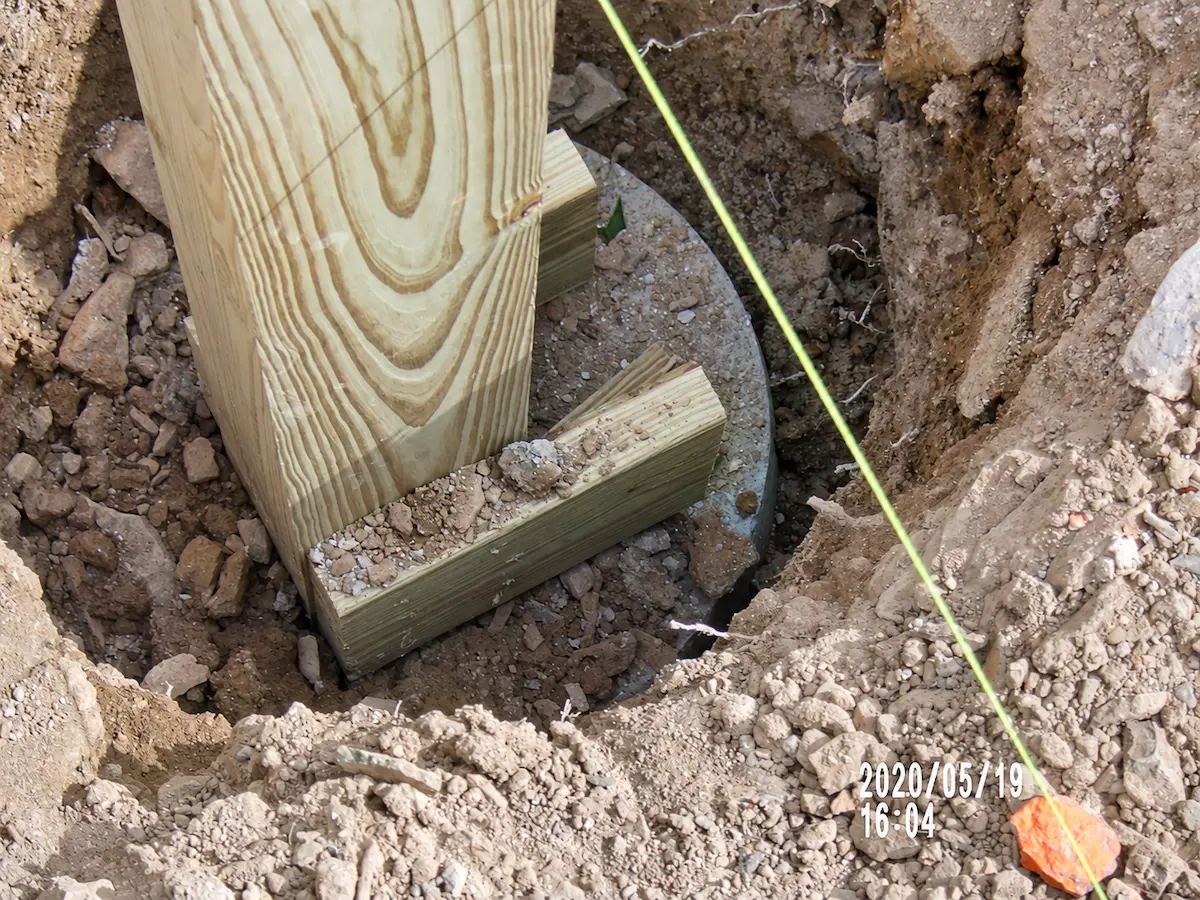 Embedded wood post bearing on a concrete footing with uplift restraint blocks